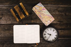 elevated-view-diary-map-clock-wooden-background